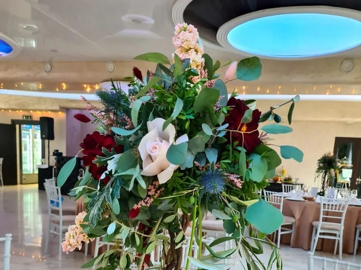 Aranjament floral înalt pentru masa invitaților, montat de Florăria Dana într-o sală de nuntă din Cluj